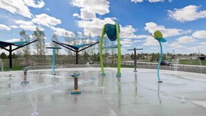 An outdoor water play area with multiple water jets and colorful structures. - The Northside Nest (Lethbridge)
