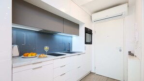 A modern kitchen with white cabinets, a blue backsplash, a built-in oven, and a white door. - Hedera Estate, Hedera Studio 4 (Dubrovnik)