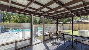 A covered patio with a view of a backyard swimming pool, outdoor furniture, and a large air conditioning unit. - Pool Home in Ocala -Casa Oasis (Ocala)