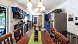 A modern kitchen with blue cabinets, a stainless steel refrigerator, and a dining table with chairs. - Pool Home in Ocala -Casa Oasis (Ocala)