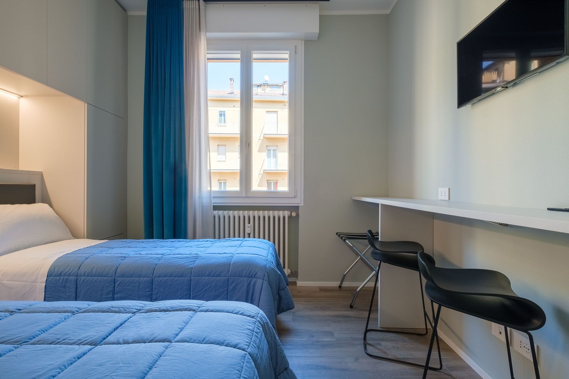 A hotel room with two beds, a desk, and a chair.