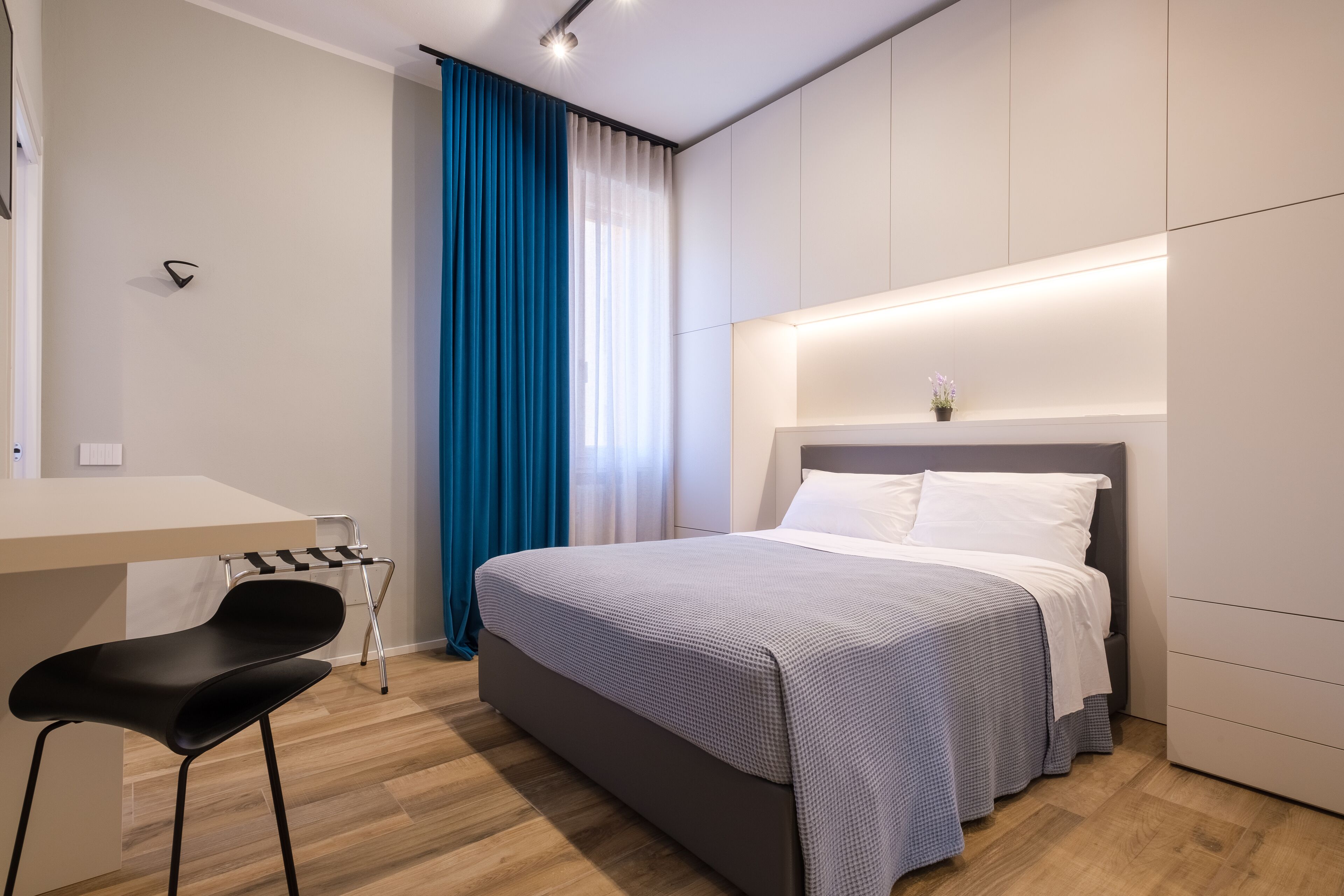 A modern bedroom with a bed, a desk, and a chair.