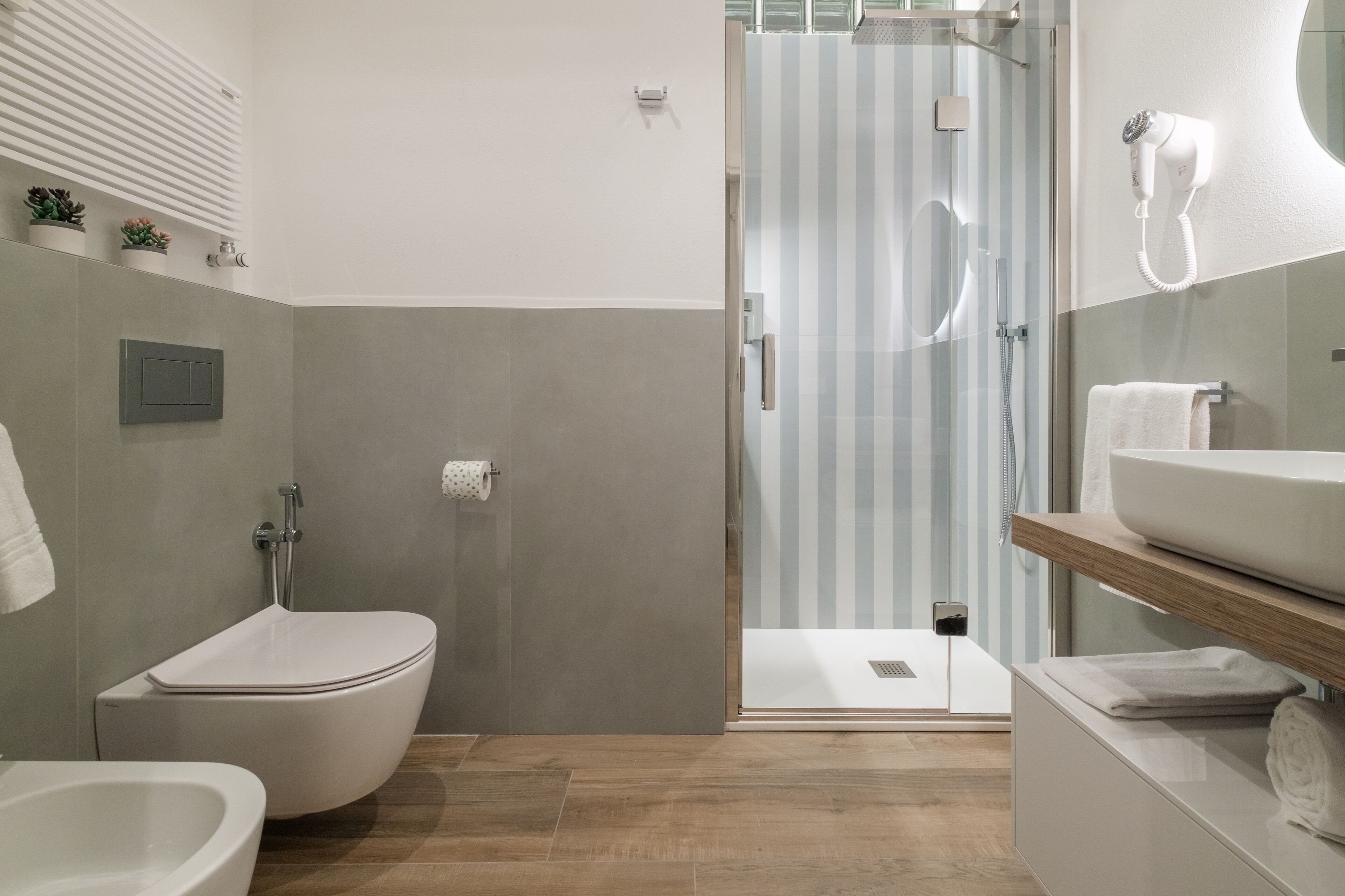 A modern bathroom with a toilet, bidet, and shower area.