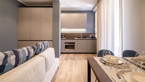 Une cuisine moderne dotée d’appareils électroménagers intégrés et d’un coin repas avec une table dressée pour quatre personnes.