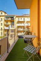 Un balcone con erba sintetica, un tavolo e sedie.