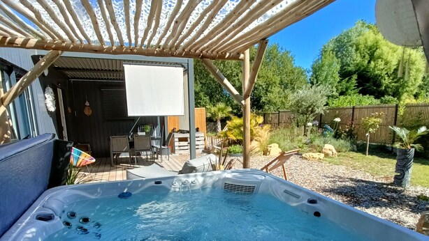 Ett bubbelbad under en träpergola med utsikt över en trädgård och en uteplats.