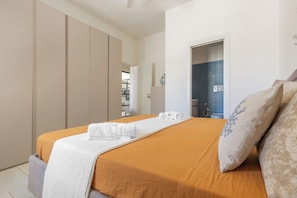 Habitación de hotel con cama, armario, baño con ducha y puerta que da a otra habitación.