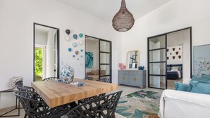 A modern living room with a wooden dining table, black chairs, a hanging light fixture, and a sofa. - Villa Anita by BarbarHouse (San Pietro in Bevagna)