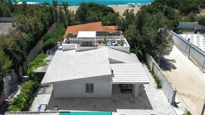 A building with a tiled roof, a patio area, and a view of the ocean.