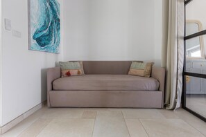 A neutral-toned sofa with patterned cushions, a large abstract painting on the wall, and a view through a glass door.