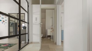 A corridor with a glass door leading to a bathroom, a tiled floor, and a visible toilet.