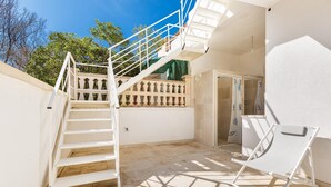 A staircase leading to a balcony, a white chair, and a tiled floor.