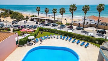 A pool area with lounge chairs, a swimming pool, and a view of the beach and ocean.