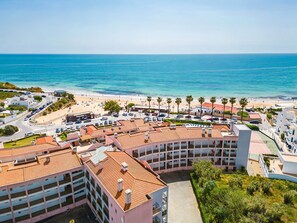 Ein Hotel an der Küste mit mehreren Etagen, Blick auf den Strand und einem Parkplatz.