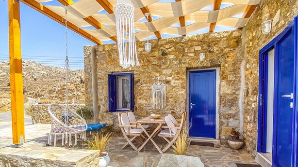 Eine Steinterrasse mit Pergola, Sitzgelegenheiten im Freien und einer Steinmauer.
