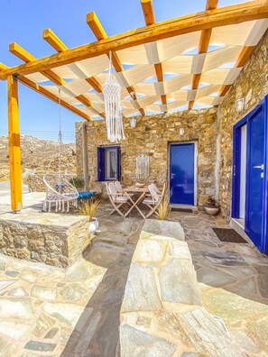A stone patio with a pergola, outdoor seating, and a stone wall.
