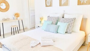 Ein modernes Schlafzimmer mit einem großen Bett, vielen Kissen, einem Nachttisch, einem Spiegel und Wandbildern.