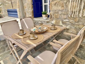 A wooden table set with placemats, a tray of seashells, and two cups.