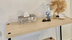 Ein Holzkonsolentisch mit Spiegel, Taschentuchbox, einer Vase mit getrockneten Blumen und einem Brillenpaar.