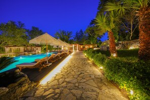 A stone pathway leading to a pool area with lounge chairs and a covered seating area. - Nuup Hotel (Marmaris)