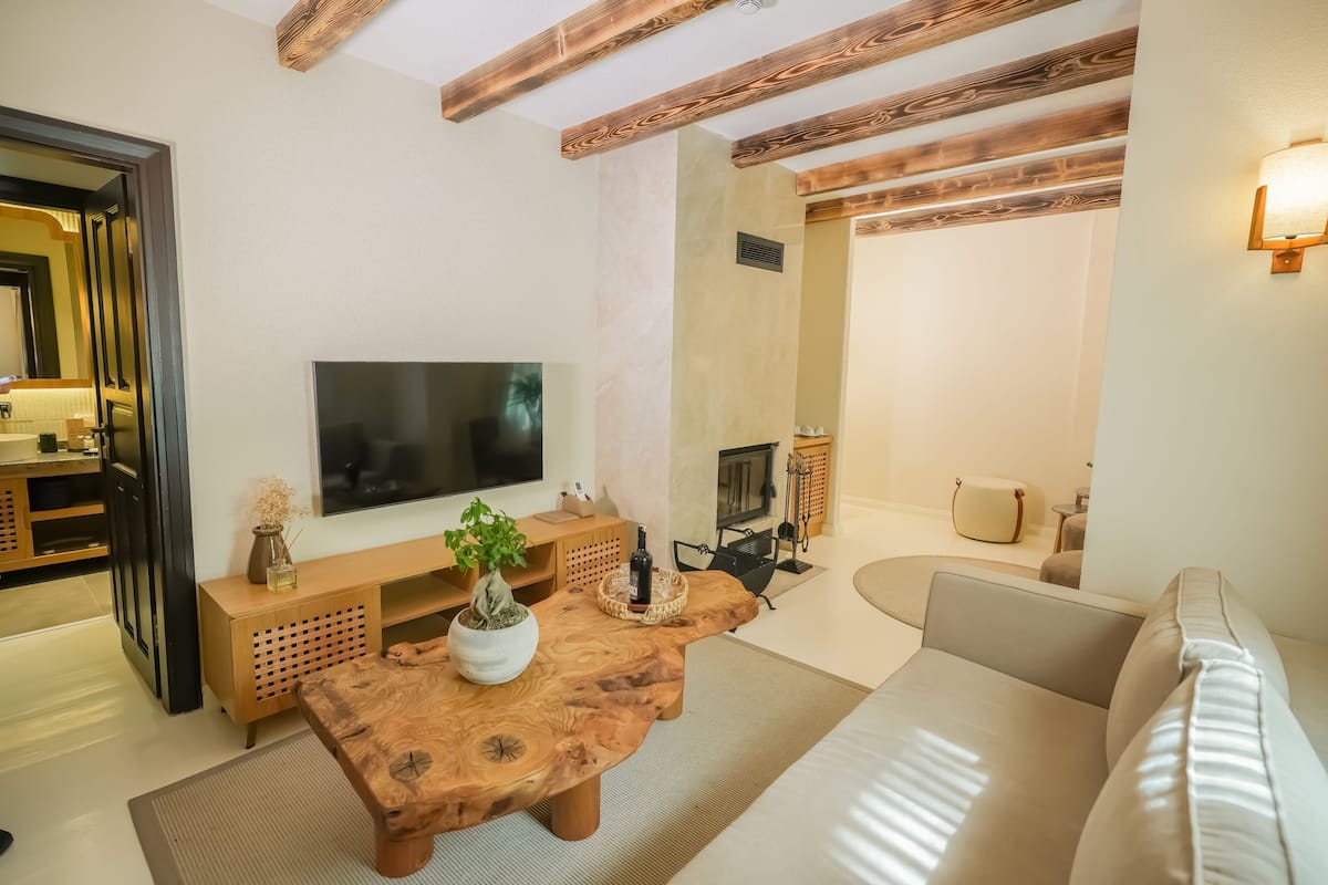 A modern living room with a wooden coffee table, a flat-screen TV, a sofa, and a fireplace.