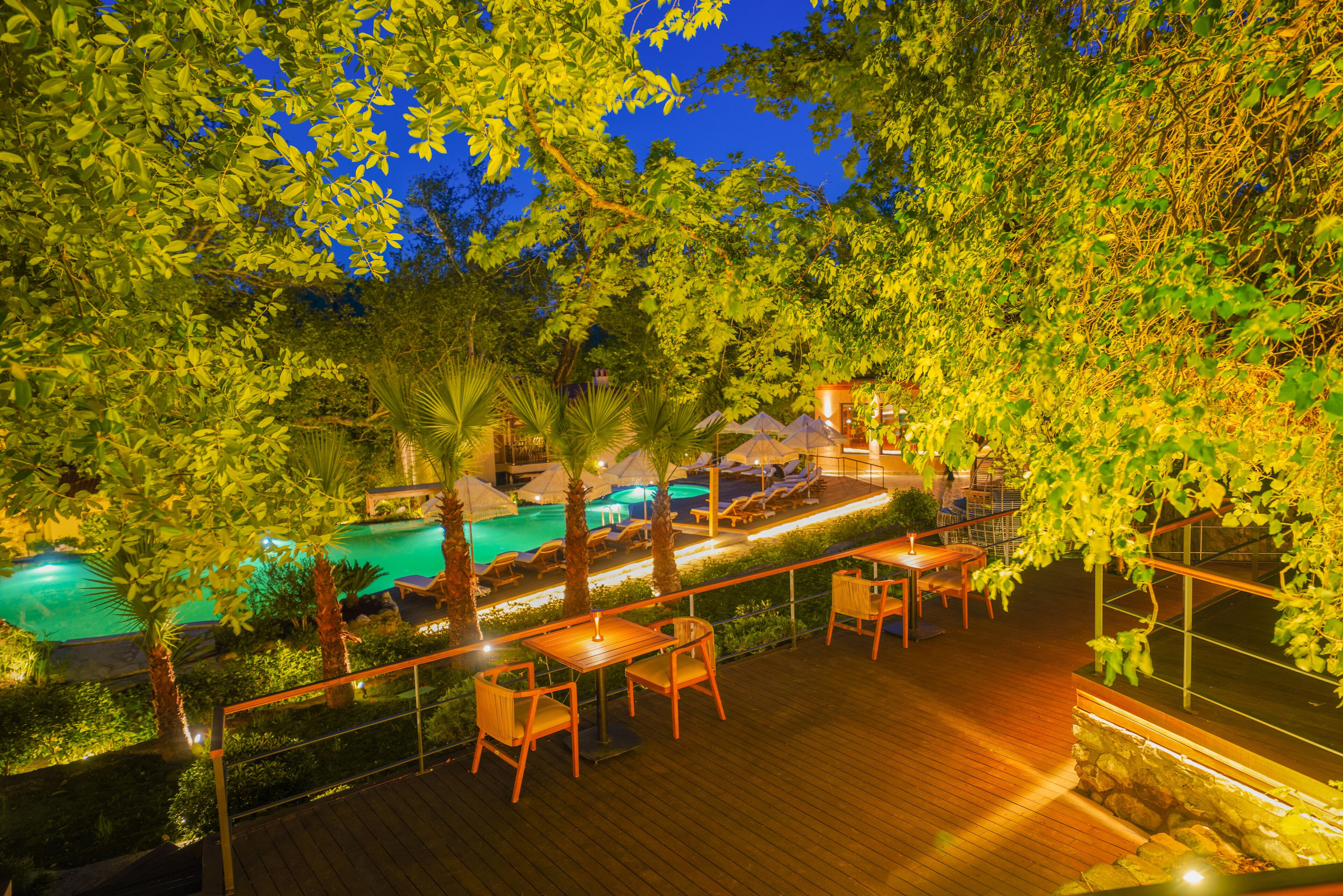 A nighttime outdoor area with a pool, wooden deck, and lounge chairs.