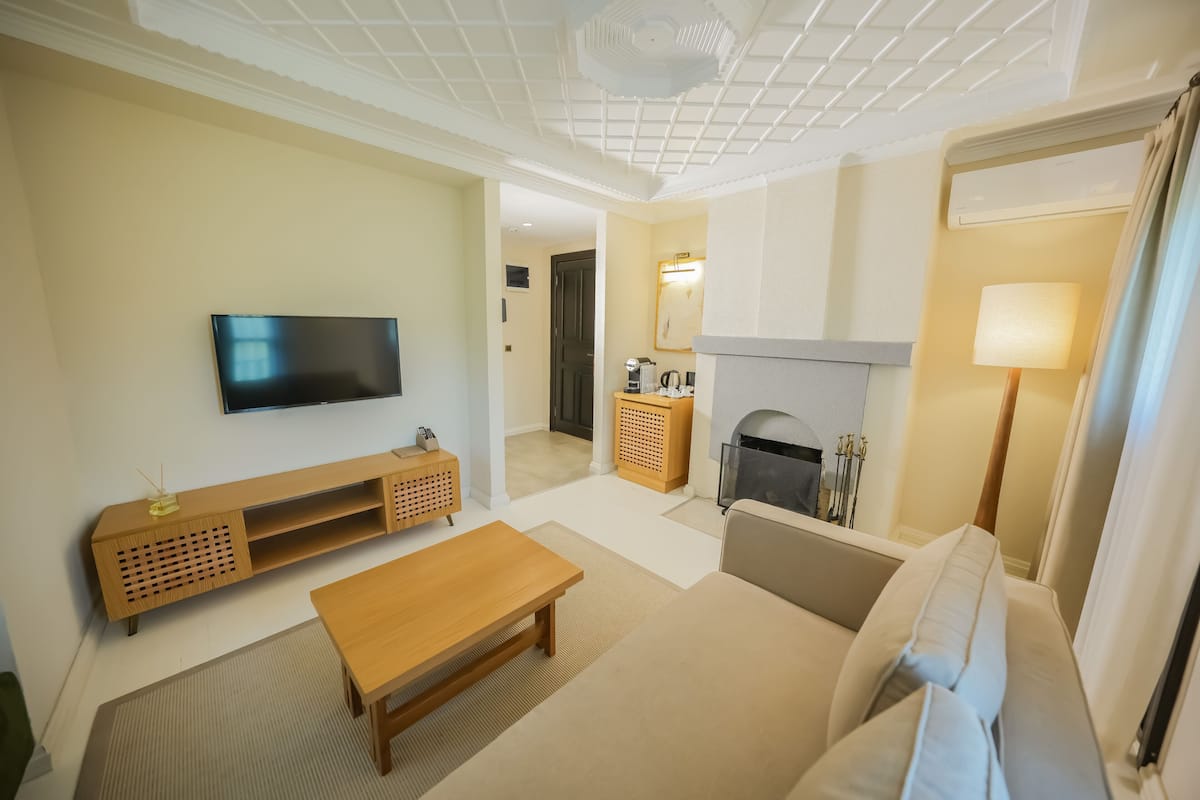 A living room with a TV, wooden entertainment unit, sofa, and a fireplace.
