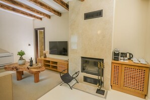 A modern living room with a fireplace, TV, wooden furniture, and a coffee station. - Nuup Hotel (Marmaris)