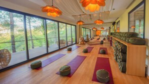 A spacious room with large windows, wooden flooring, and multiple yoga mats and cushions arranged for practice. - Nuup Hotel (Marmaris)