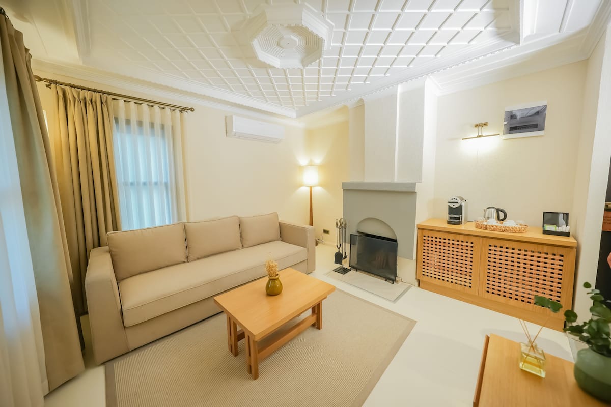 A living room with a sofa, coffee table, fireplace, and a wooden cabinet.