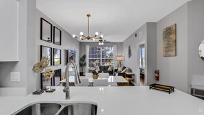 Une cuisine moderne dotée d’un évier à deux bacs, d’un lustre et d’un coin repas avec une table et des chaises.
