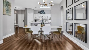 Un espace de salle à manger moderne avec une table blanche, des chaises dorées et un lustre.
