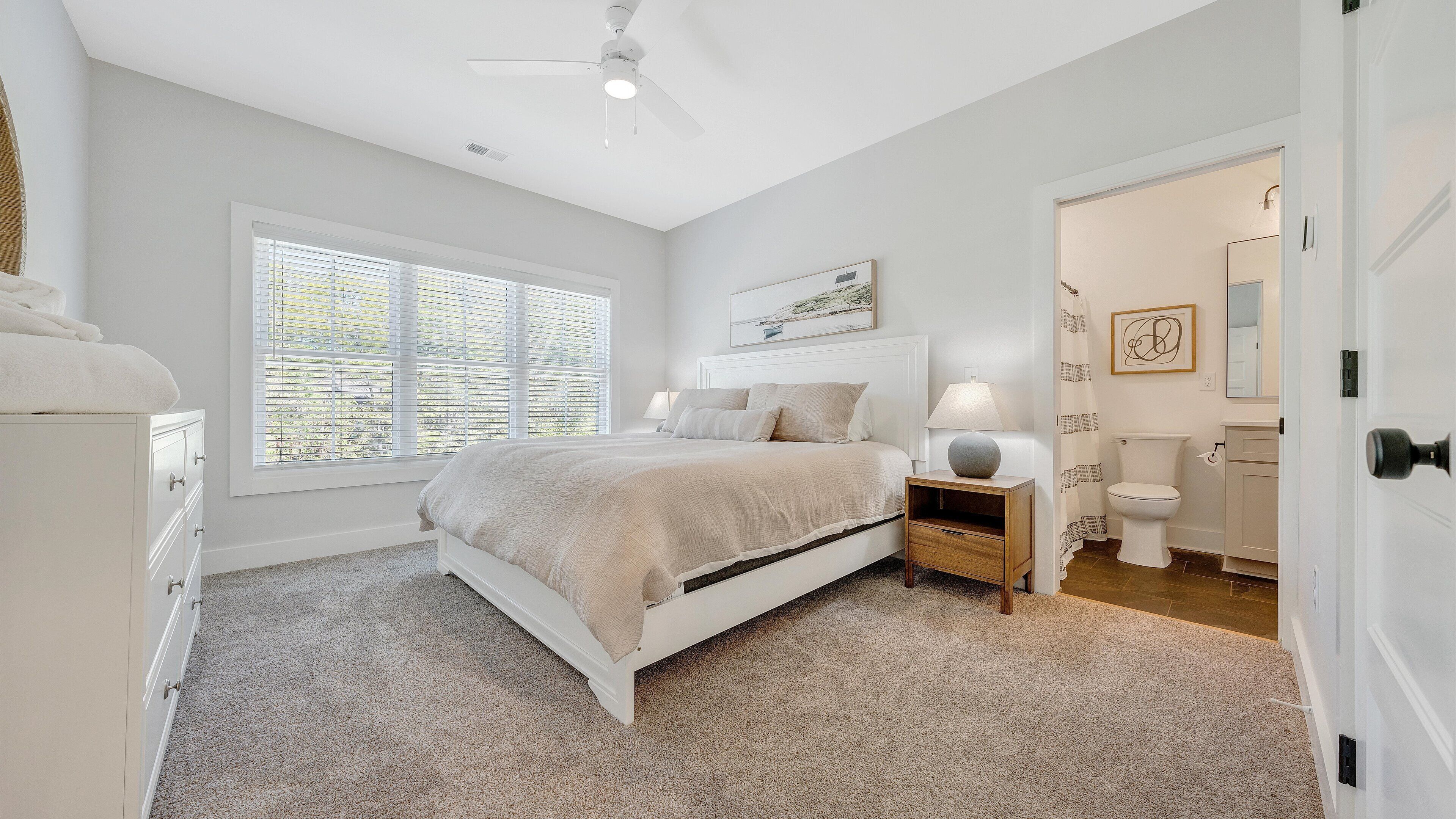 A bedroom with a bed, bedside table, and a window.