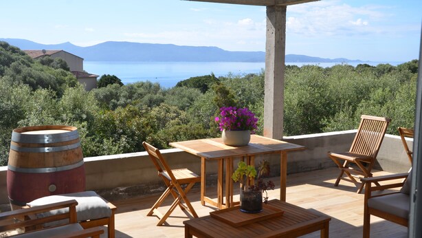 An outdoor patio with wooden furniture, a barrel, and a potted plant. - Haut de Villa, Calme, vue mer (Serra-di-Ferro)