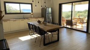 A modern kitchen with a wooden table, black chairs, and a large window. - Haut de Villa, Calme, vue mer (Serra-di-Ferro)