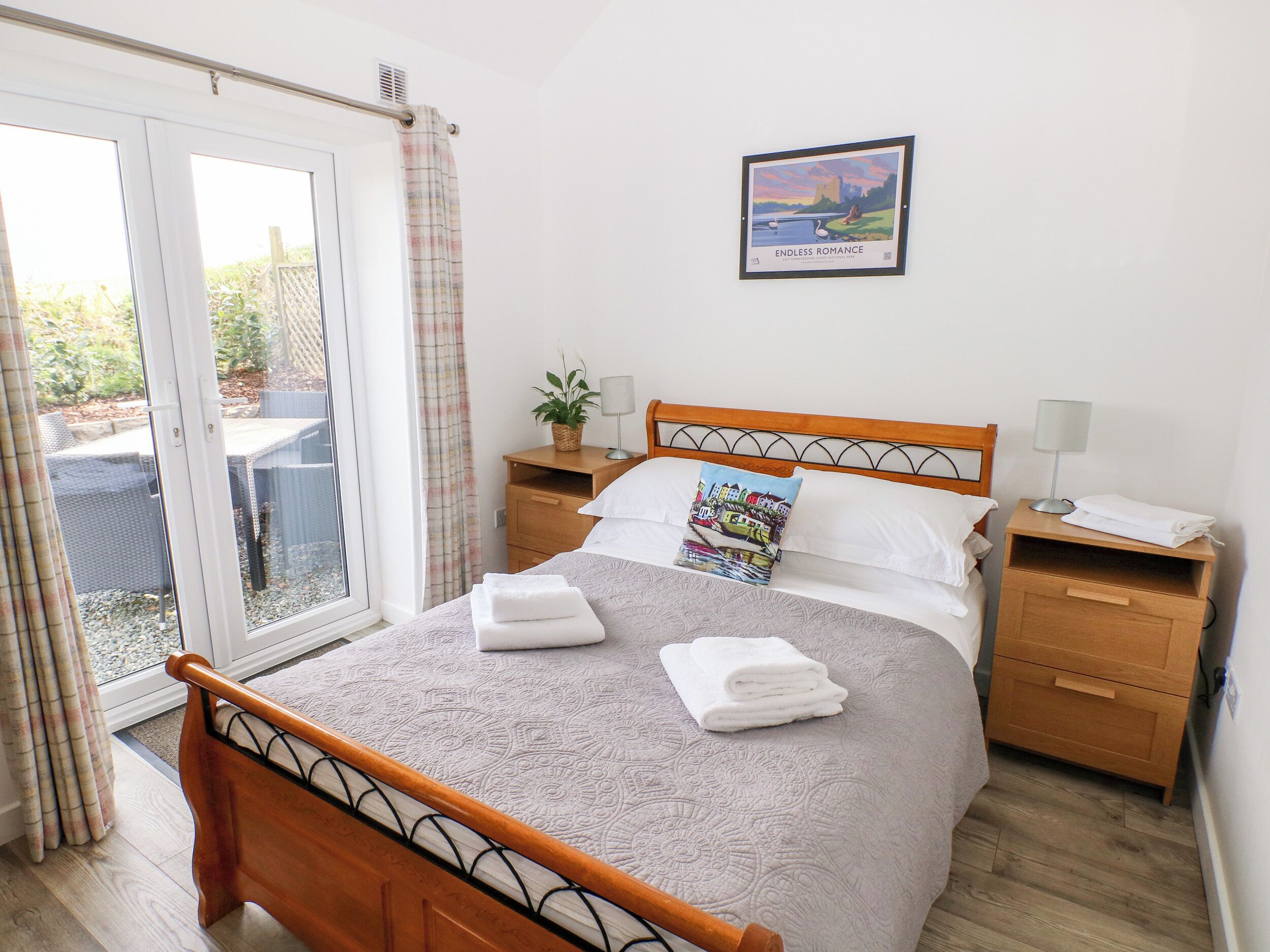 Une chambre à coucher comprenant un lit, une table de chevet, une lampe, une plante en pot et une vue sur l’extérieur grâce à une porte coulissante.