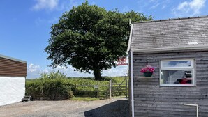 A small wooden building with a window and a flower box. - Dairy Cottage (Whitland)