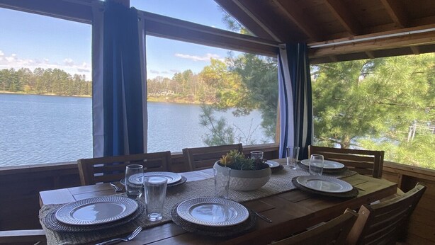 Ein Esstisch für vier Personen mit Blick auf einen See und Bäume.