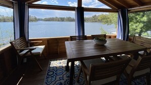 Eine Holzterrasse mit Tisch und Stühlen mit Blick auf einen See.