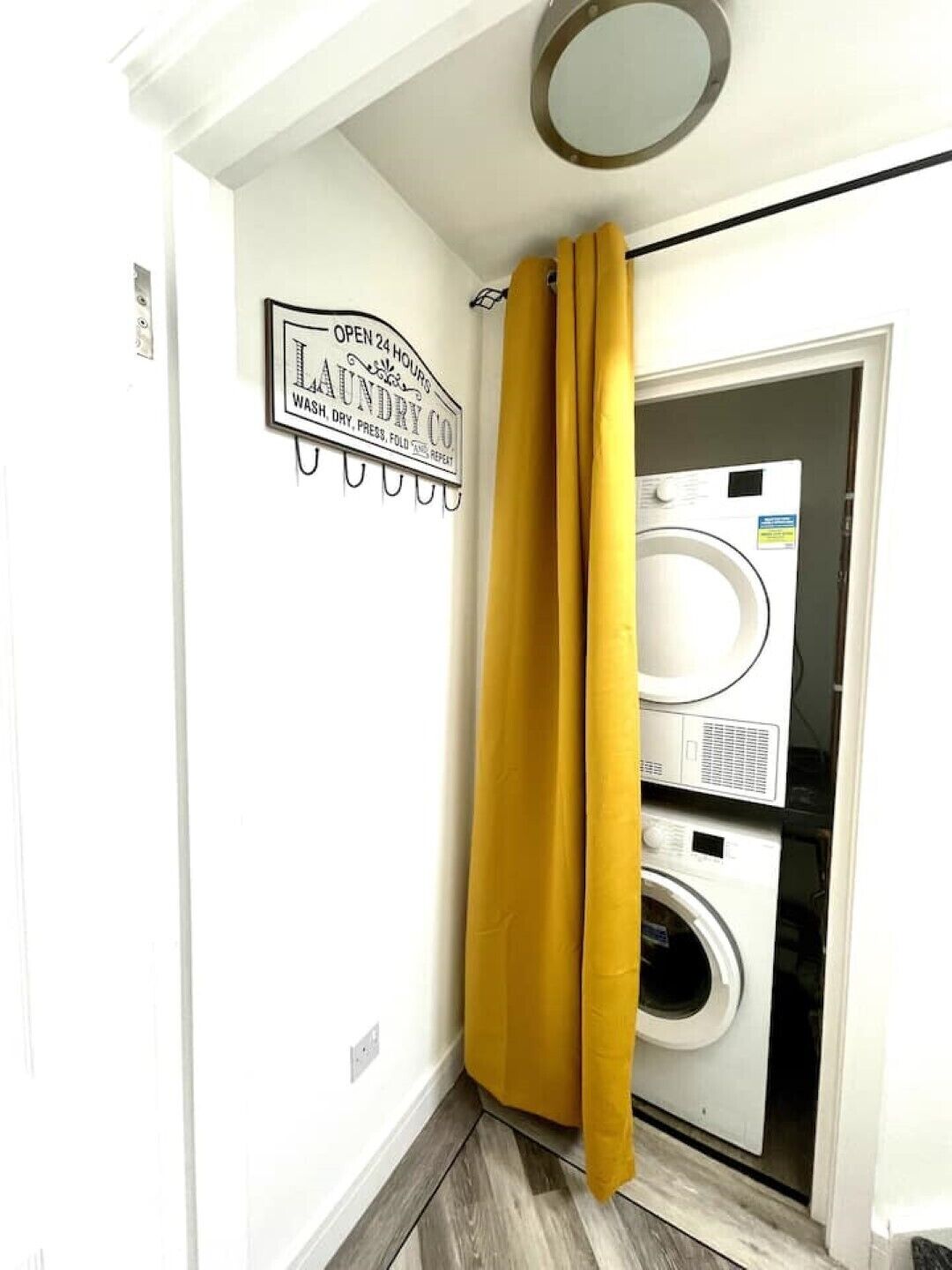Une buanderie avec une pancarte indiquant un service disponible 24 heures sur 24, une machine à laver et un sèche-linge.