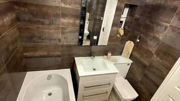 A modern bathroom with a bathtub, sink, and toilet.