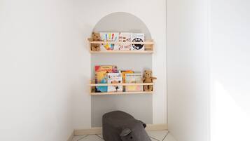 Un angolo di una stanza con una libreria piena di libri per bambini e un peluche.