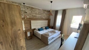 A bedroom with a wooden headboard, a bed with white linens, a nightstand, and a desk with a chair. - Cat Kapi Alacati (Cesme)