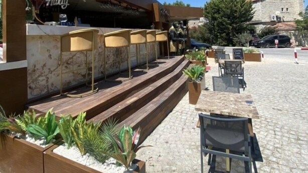 An outdoor seating area with a bar, wooden steps, and planters. - Cat Kapi Alacati (Cesme)