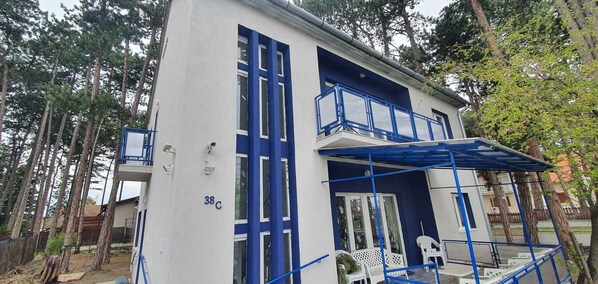 A two-story building with a white exterior and blue accents, including a balcony and railings.