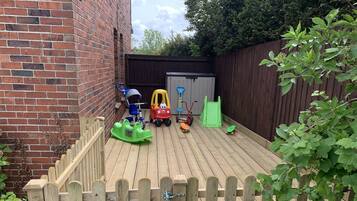 Guests can enjoy a spacious outdoor area with a brick wall, wooden fence, and lush greenery.