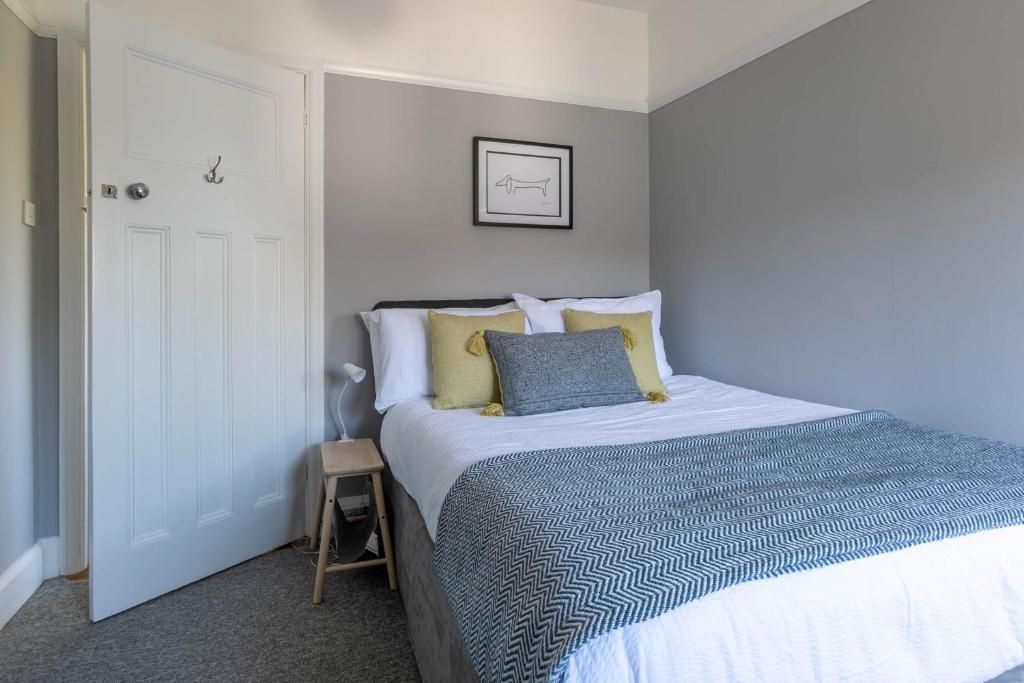 Quarto com cama, mesa de cabeceira, porta e quadro na parede.