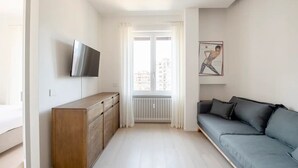 Ein modernes Wohnzimmer mit grauem Sofa, Holzschrank und flachbildfernseher an der Wand.