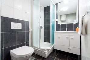 A modern bathroom with a glass-enclosed shower, a white toilet, and a vanity with a mirror. - Adriatic Queen Residence (Split)