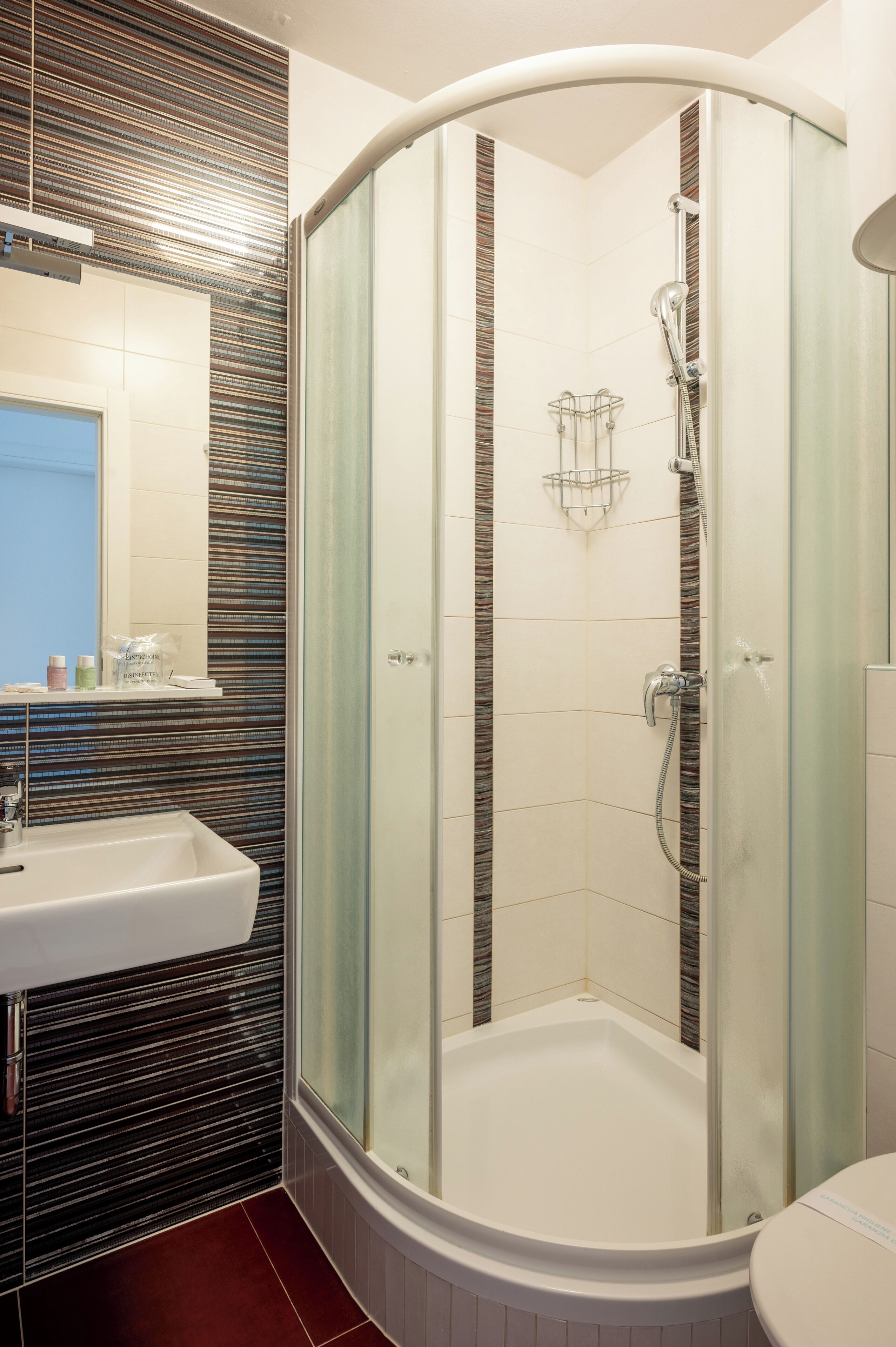 Un baño moderno con ducha de vidrio, lavamanos y espejo.
